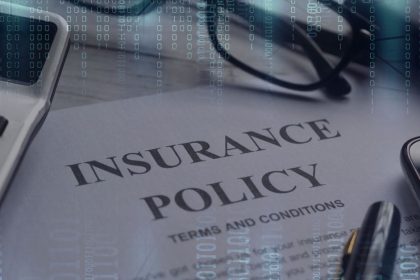 Insurance Policy on table with technology around to depict cyber insurance